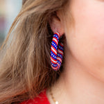 Close-up of a person wearing red, white, and blue hoop earrings.