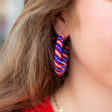 Close-up of a person wearing red, white, and blue hoop earrings.
