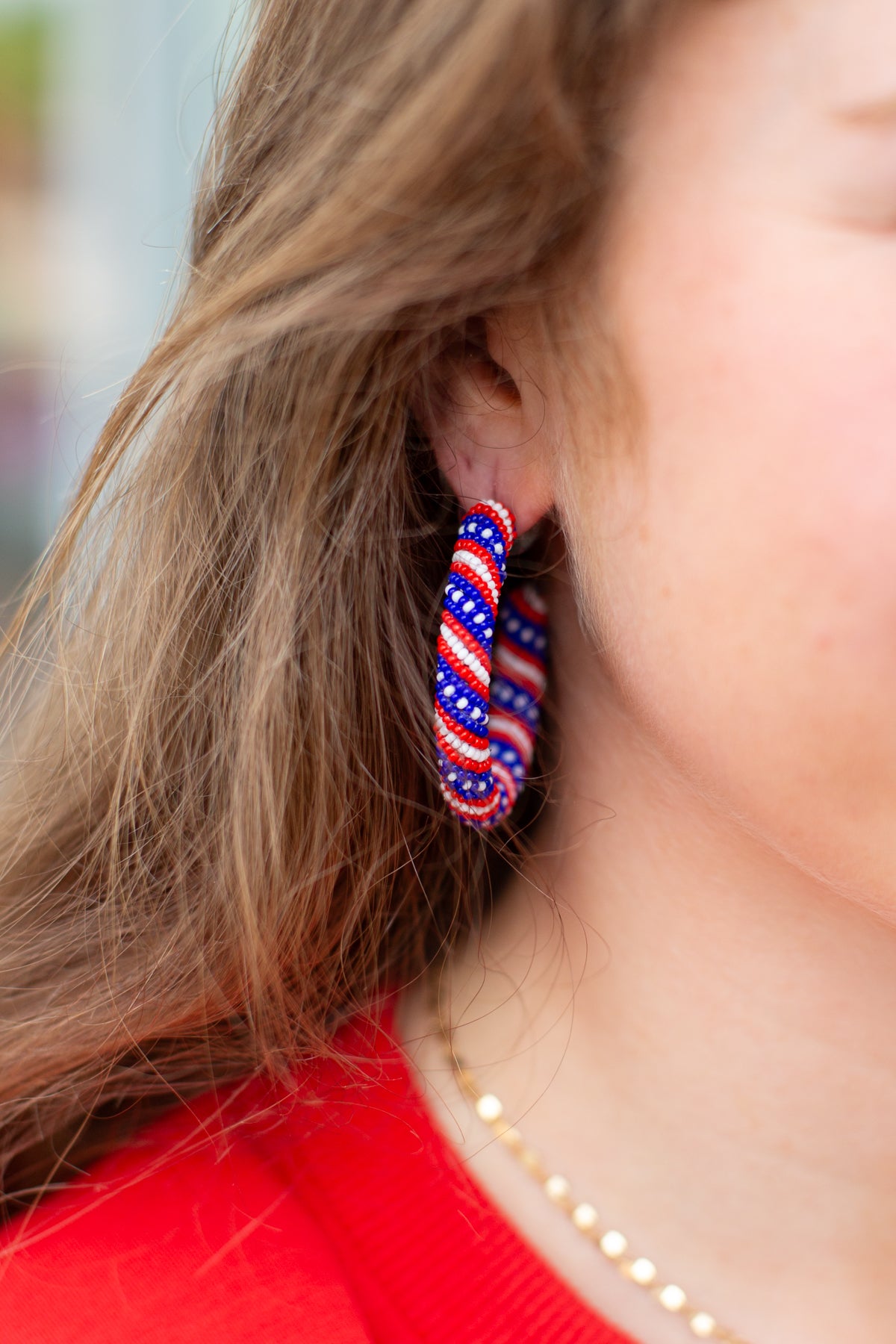 Close-up of a person wearing red, white, and blue hoop earrings.