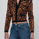 A cropped long-sleeve knit cardigan with a brown and black leopard print, black collar, and black button placket, worn by a model with blue jeans against a light gray background.