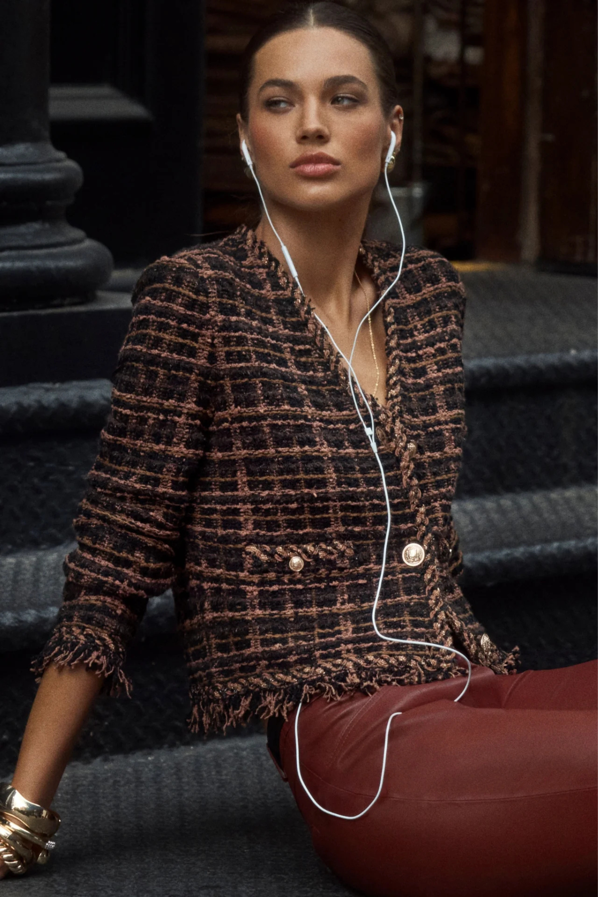 Model wearing a brown cardigan jacket with textured knit detailing and fringe accents.