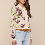 Woman wearing a floral sweater and light blue jeans against a beige background