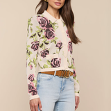 Woman wearing a floral sweater and light blue jeans against a beige background