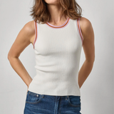 Woman wearing a white ribbed tank top with red and orange trim and blue jeans on a light gray background