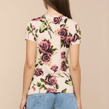 Woman wearing a floral top and denim shorts on a beige background