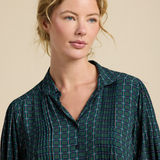 Woman wearing a green plaid shirt against a beige background