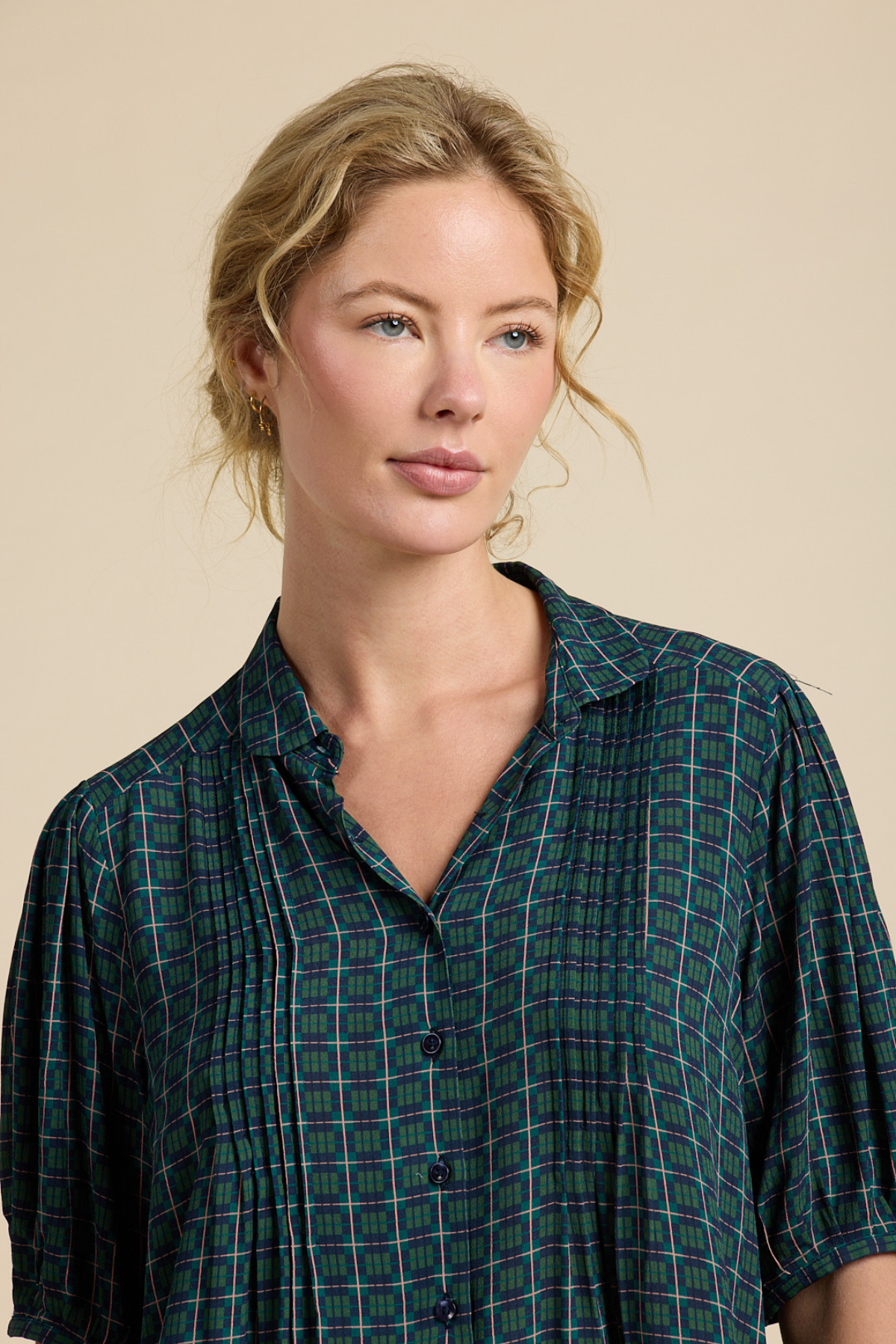 Woman wearing a green plaid shirt against a beige background
