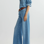 Person wearing a denim outfit with wide-leg jeans on a light gray background
