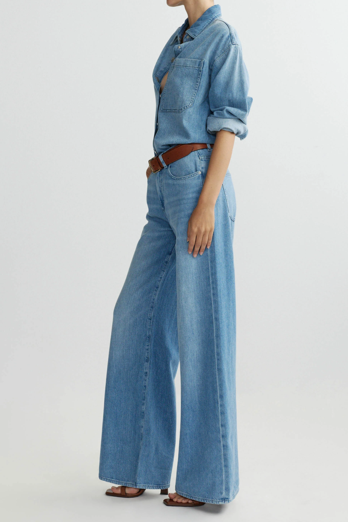 Person wearing a denim outfit with wide-leg jeans on a light gray background