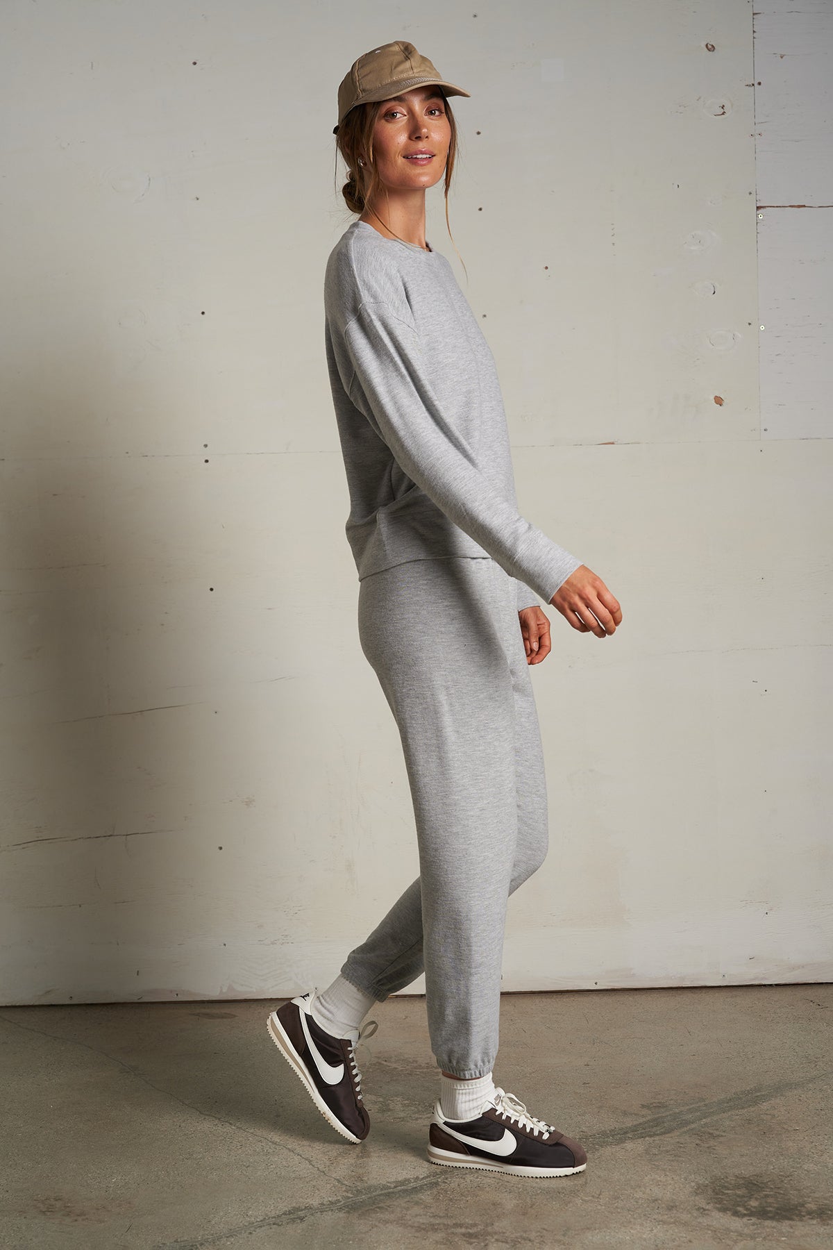 Woman wearing a light grey long-sleeve knit top with a relaxed fit, photographed against a soft neutral backdrop.