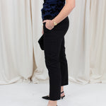 Woman wearing black chino trousers with a front hem split, styled with heels.