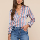 Woman wearing a patterned blouse and jeans against a beige background
