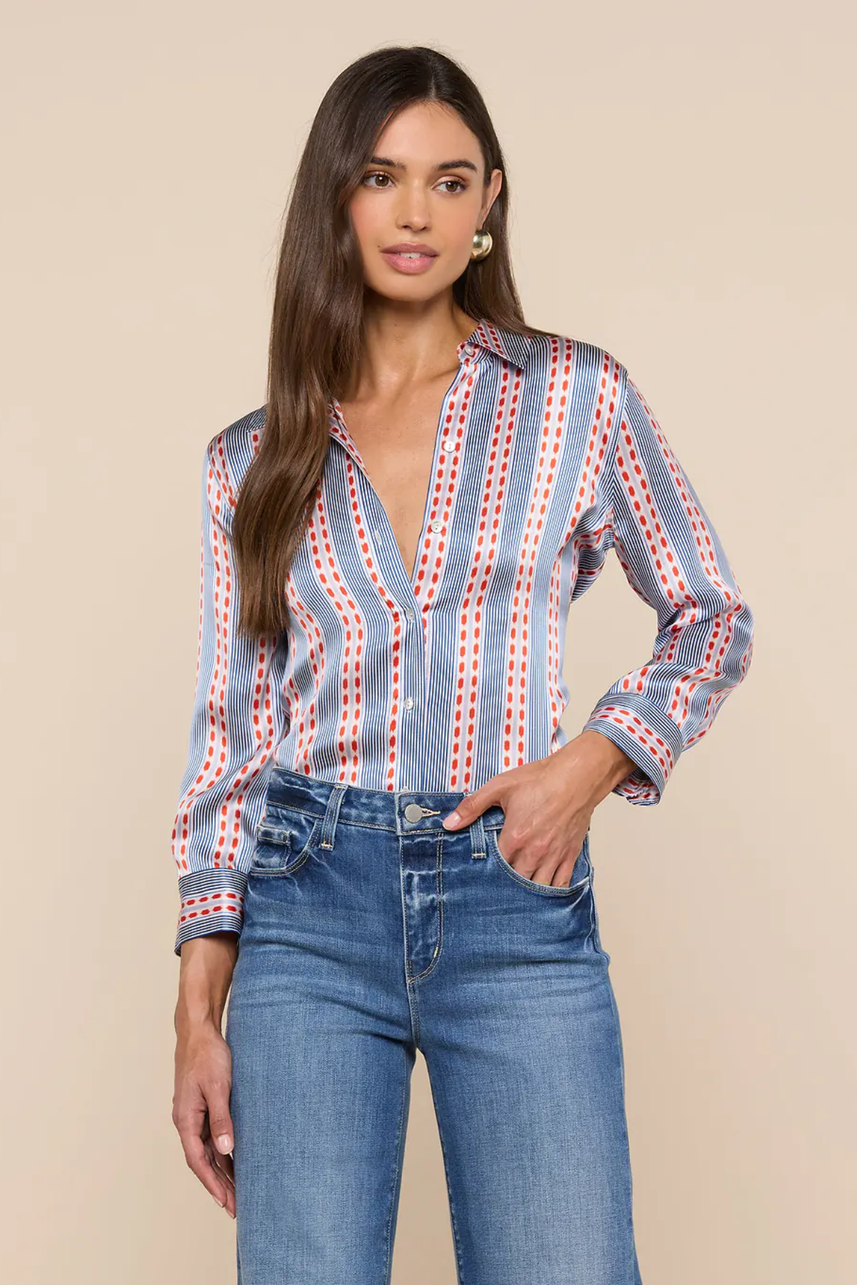 Woman wearing a patterned blouse and jeans against a beige background