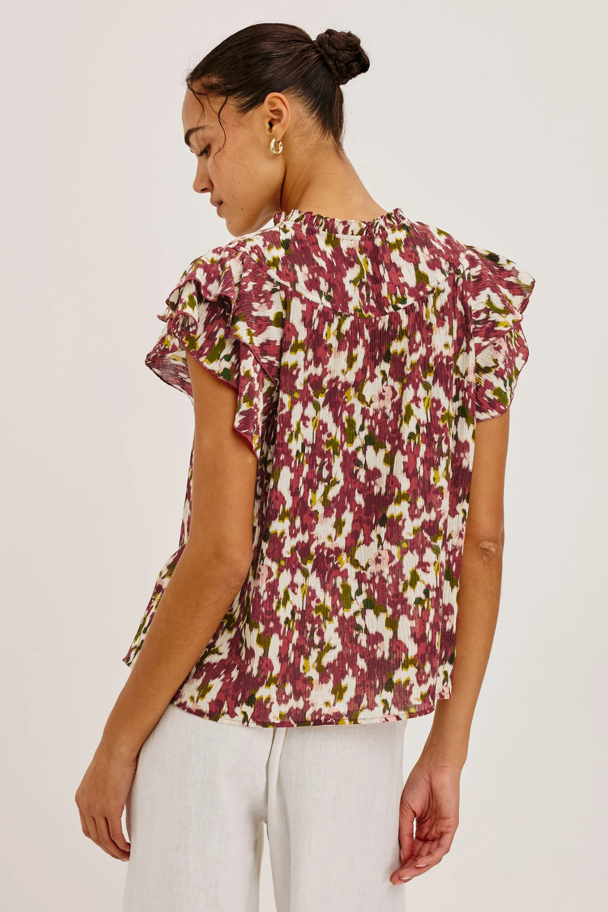 Woman wearing a floral blouse with ruffled sleeves on a white background