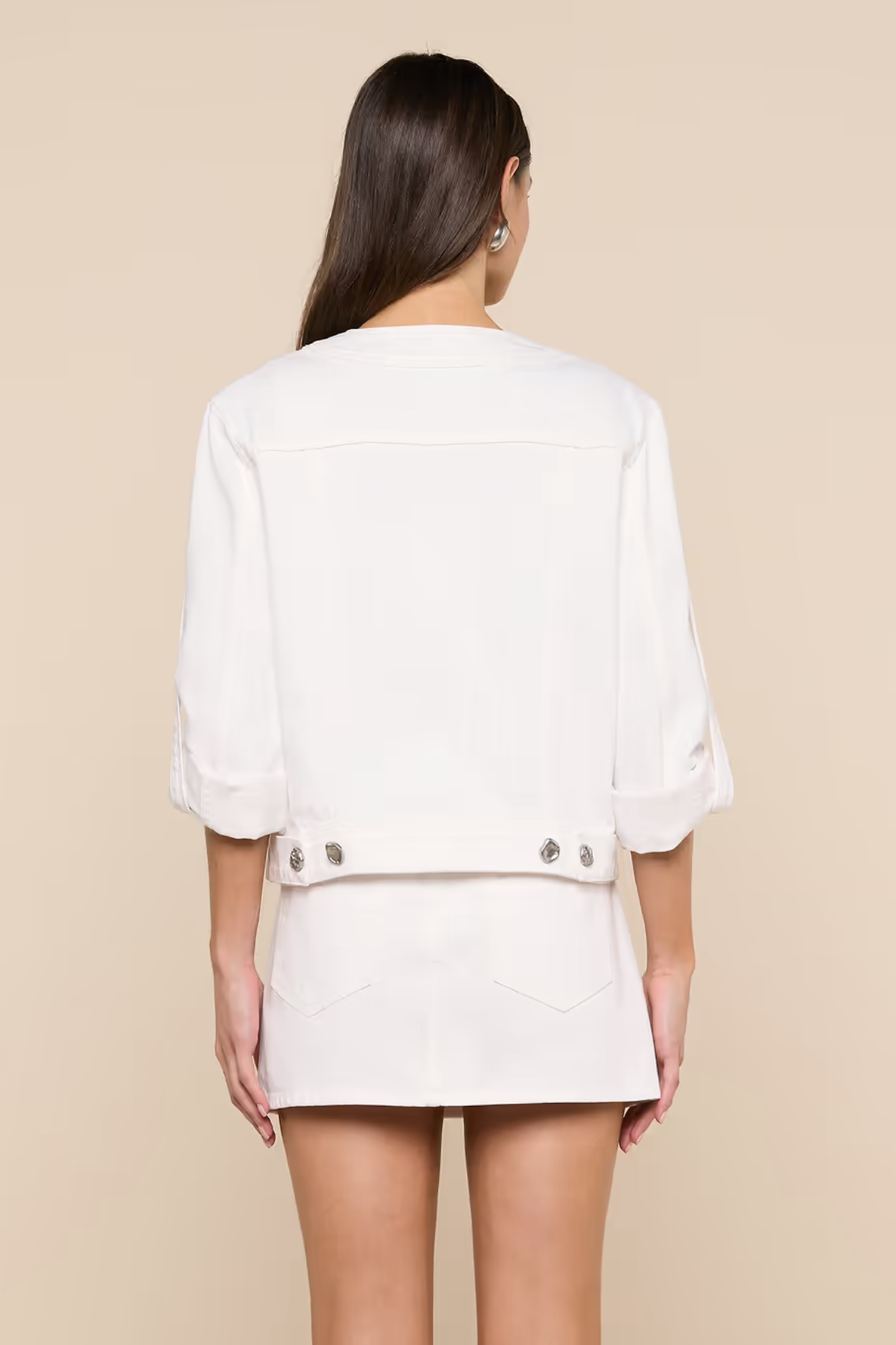 Person wearing a white outfit with a beige background