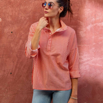 woman in striped collared button down standing by brick wall outside 