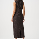 A woman shown from the back wearing a sleeveless dark brown midi dress with a textured crinkled fabric and a front slit, paired with black pointed-toe heels against a light gray studio background.
