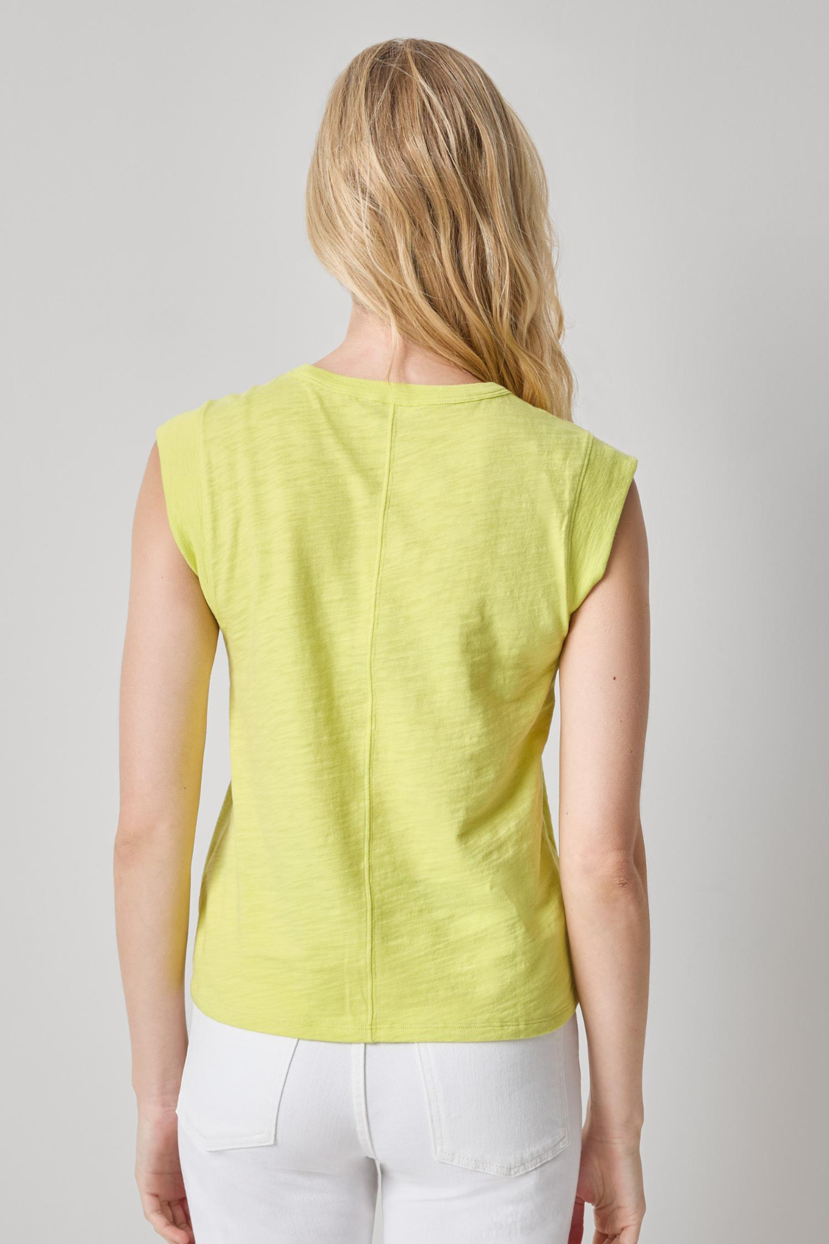 back of woman in yellow sleeveless top on white background 