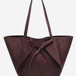 A dark plum purple suede tote bag with a large bow detail at the front and two shoulder straps, shown against a plain light gray background.