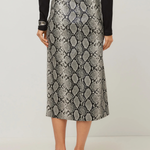 A model from the back wearing a high-waisted midi skirt with a gray and black snakeskin pattern, styled with a black top, black belt, and black strappy heels against a light gray studio background.