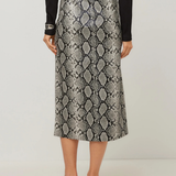 A model from the back wearing a high-waisted midi skirt with a gray and black snakeskin pattern, styled with a black top, black belt, and black strappy heels against a light gray studio background.