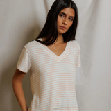 Woman wearing a white striped shirt against a plain background