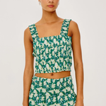 Woman wearing a green and white floral dress on a plain background