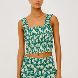 Woman wearing a green and white floral dress on a plain background