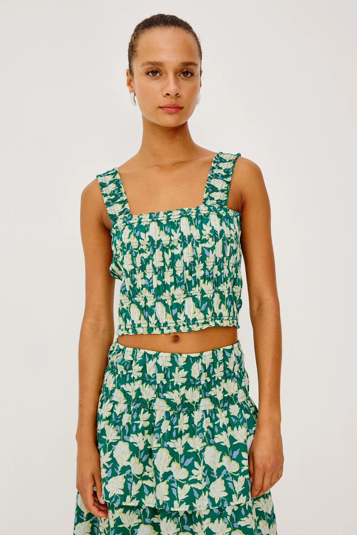 Woman wearing a green and white floral dress on a plain background