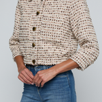 Model wearing a tweed jacket with jeans on and off white background.
