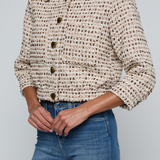 Model wearing a tweed jacket with jeans on and off white background.