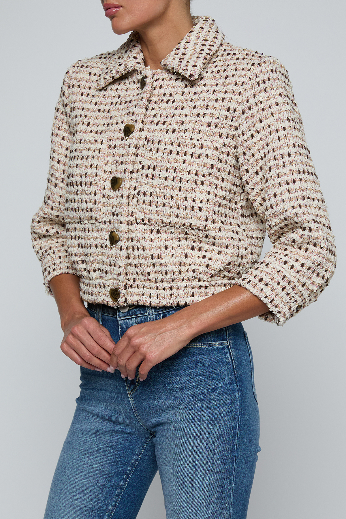 Model wearing a tweed jacket with jeans on and off white background.