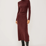 A model wearing a long-sleeve, high-neck ribbed knit midi dress in a deep burgundy color, paired with black knee-high leather boots, against a plain light gray studio background.