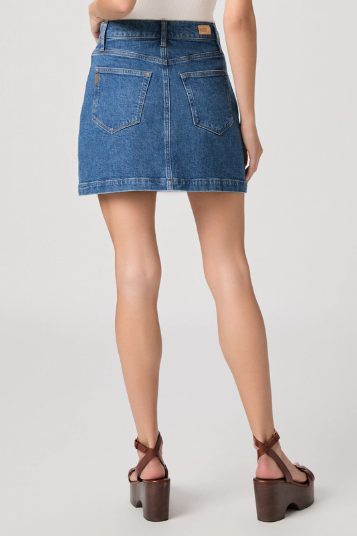 Denim skirt worn by a person on a plain background