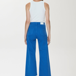 Person wearing a white sleeveless top and blue high-waisted pants on a white background