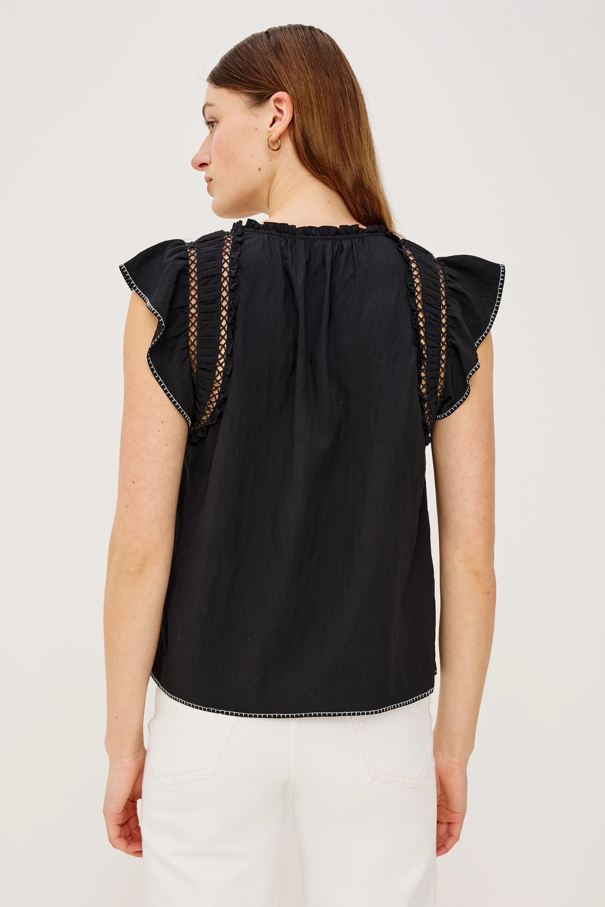 Woman wearing a black top with ruffled sleeves on a white background