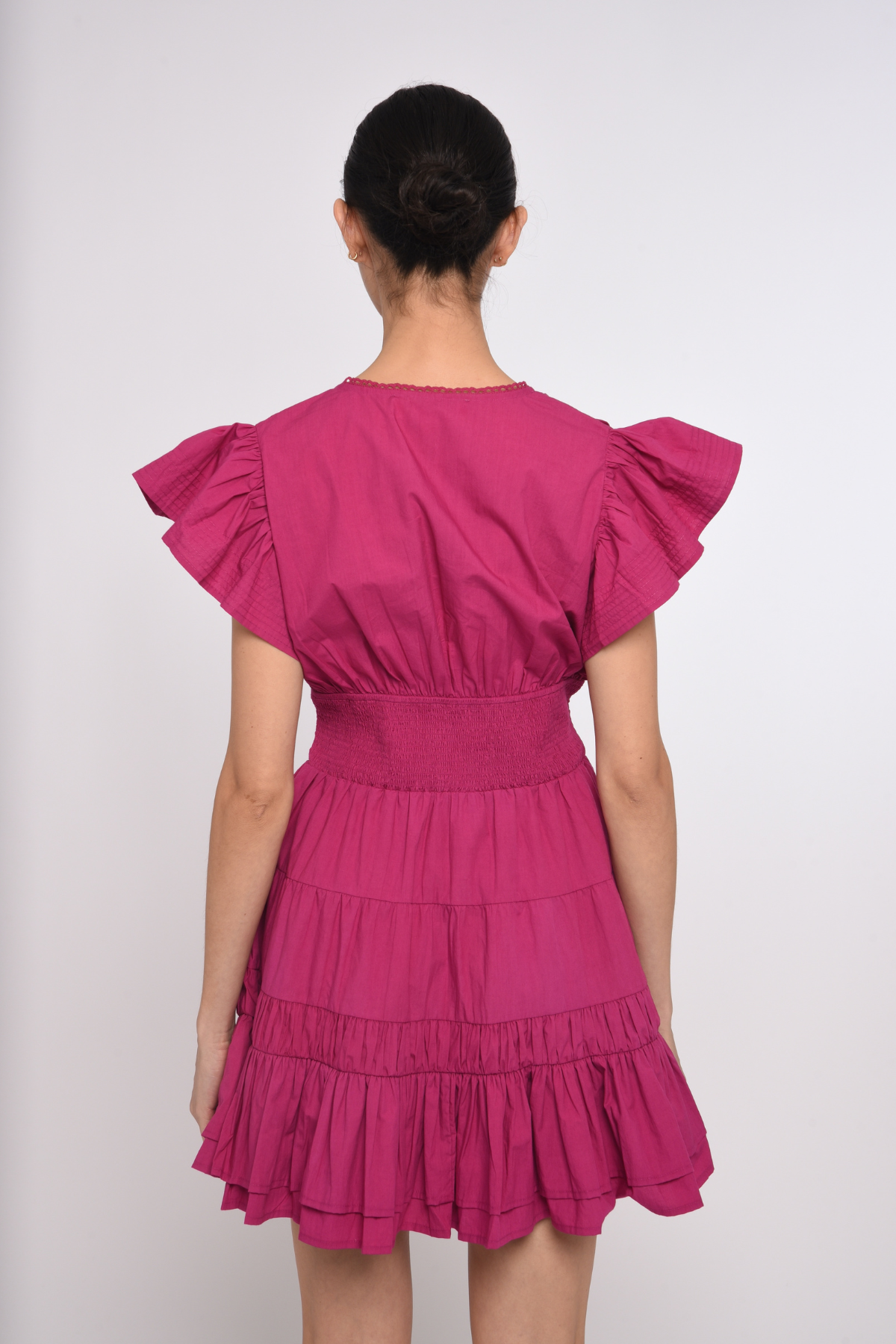 Model wearing a bright pink mini dress with a fitted waist and short sleeves.