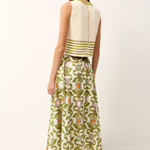 Woman wearing a white sleeveless top with green stripes and a green floral skirt on a white background