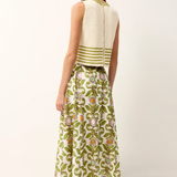 Woman wearing a white sleeveless top with green stripes and a green floral skirt on a white background
