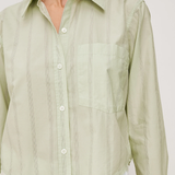 Light green button-up shirt worn by a person on a white background