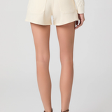 Person wearing light-colored shorts and a white top on a plain background