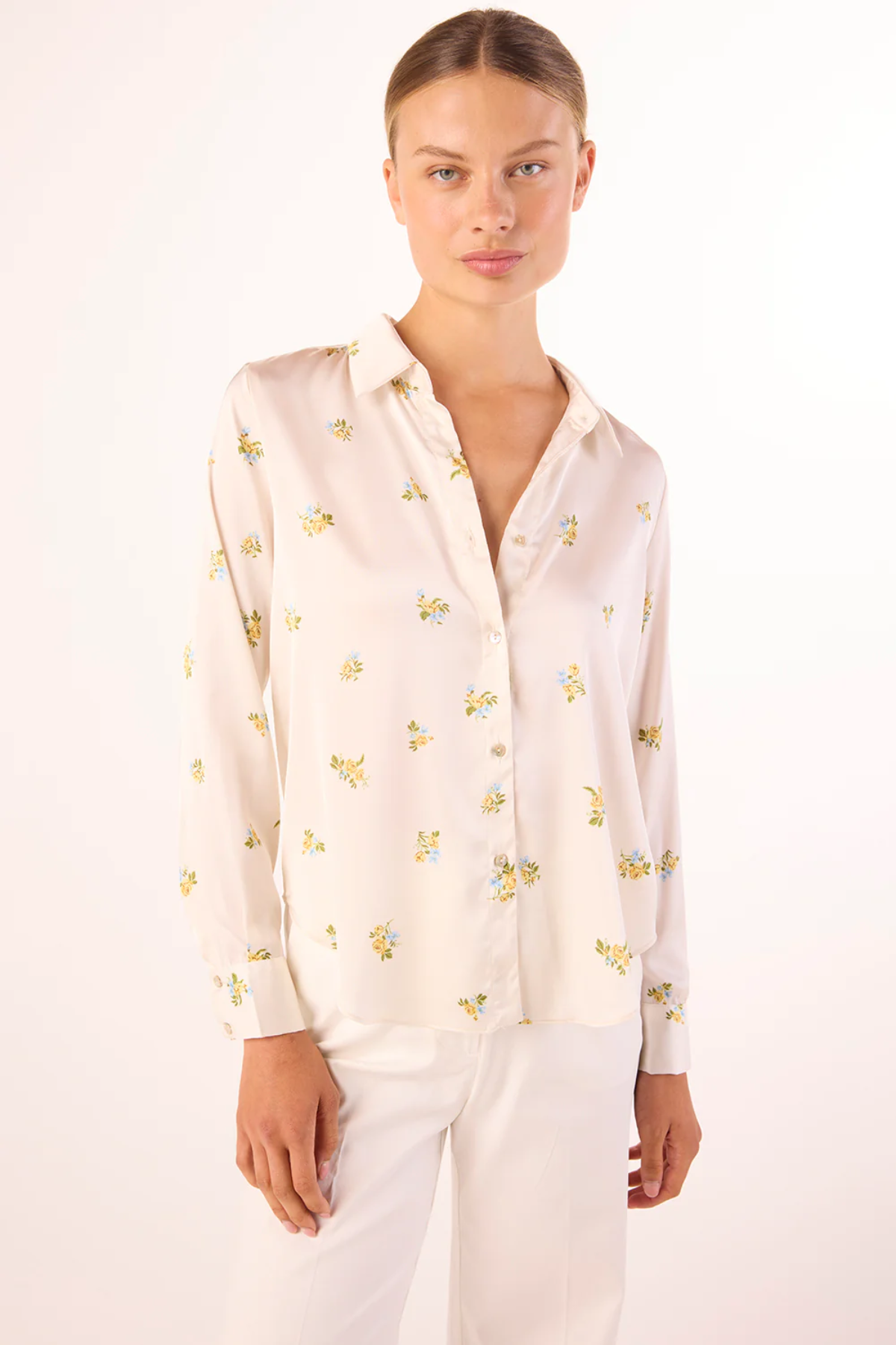 Woman wearing a cream-colored blouse with small yellow patterns on a white background