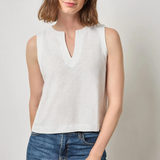 Woman wearing a white sleeveless top and blue jeans against a plain background