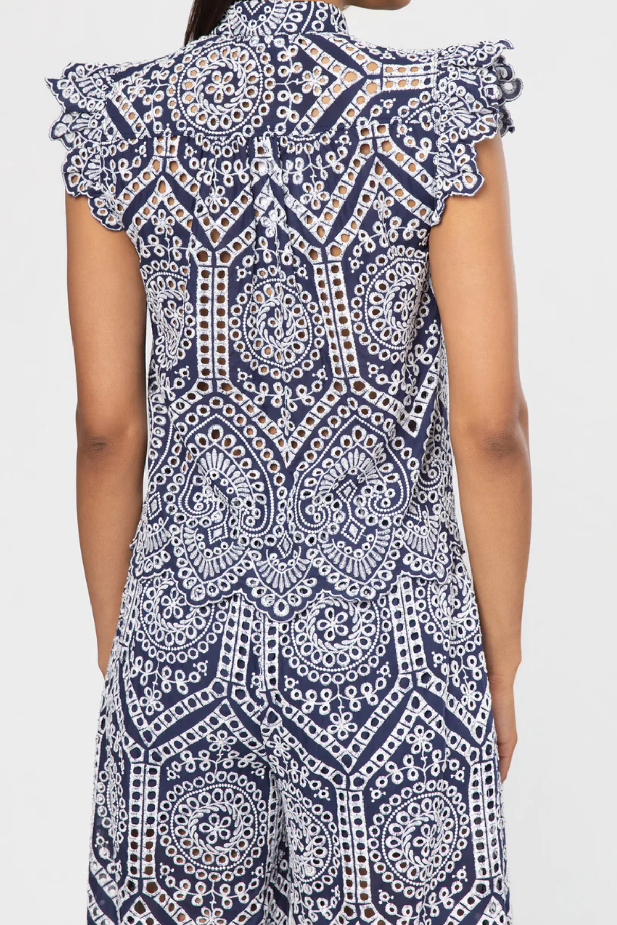 Navy and white patterned top with ruffled shoulders on a plain background