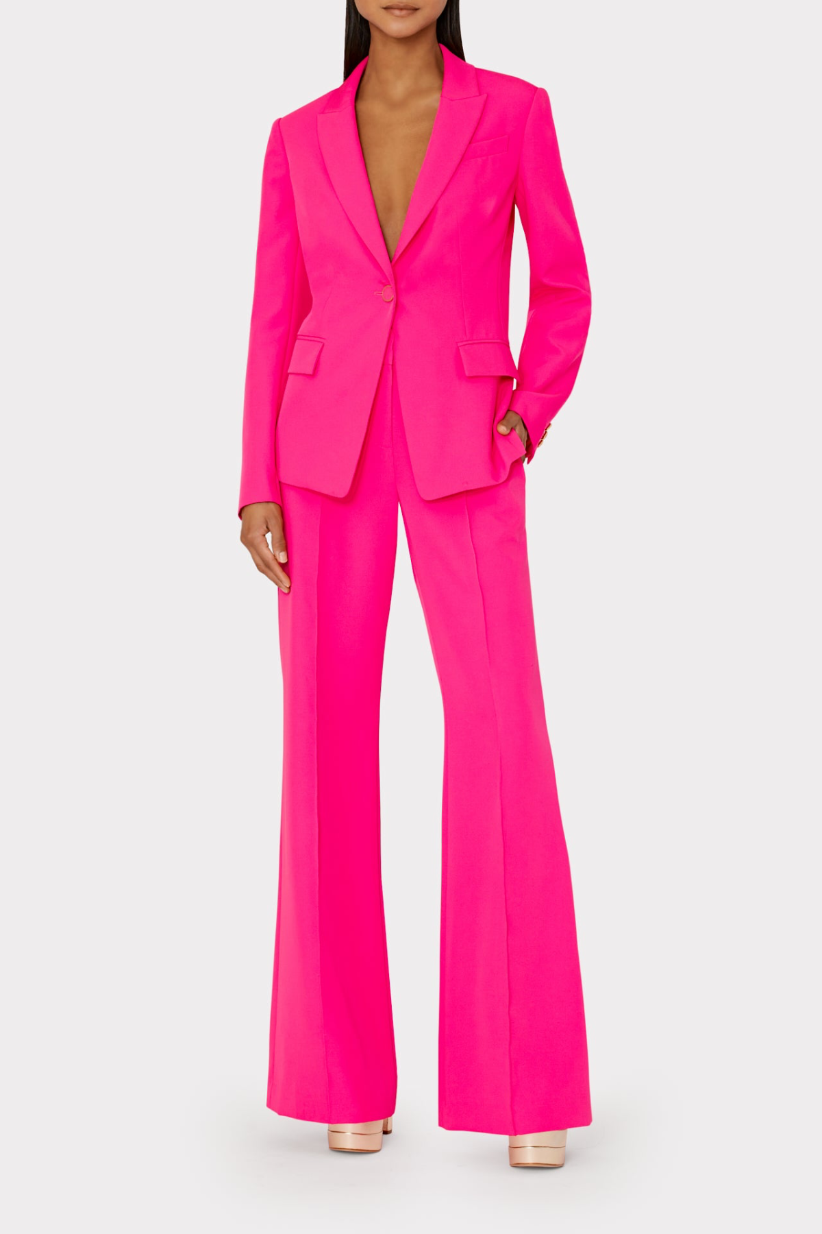 Bright pink suit with a blazer and flared pants on a white background