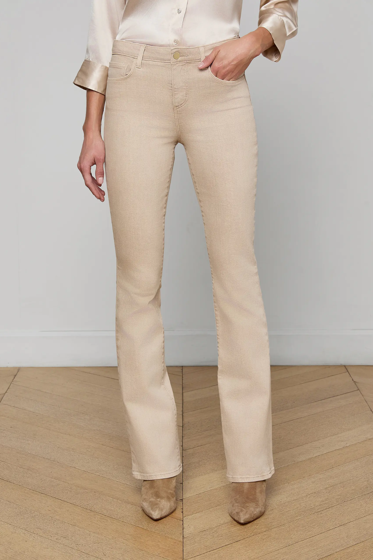 Person wearing beige pants and a white shirt against a plain background