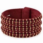 A wide, multi-strand beaded cuff bracelet in deep burgundy with metallic gold spacer beads, displayed on a clean white background.