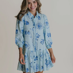 Woman wearing a blue floral dress against a plain background