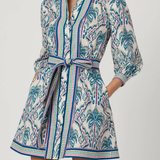 Woman wearing a patterned dress with a belt on a white background