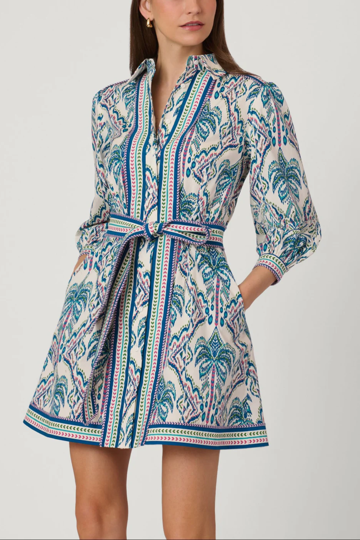 Woman wearing a patterned dress with a belt on a white background